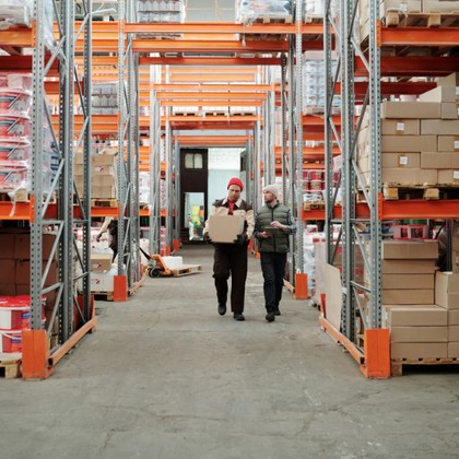 Warehouse workers moving boxes between pallet racks